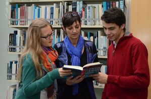 Bibliothek Studierende mit Lehrkraft in der Bibliothek